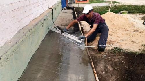 Отмостка вокруг старого дома. Процесс ремонта разрушенной отмостки