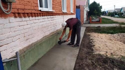 Отмостка вокруг старого дома. Процесс ремонта разрушенной отмостки